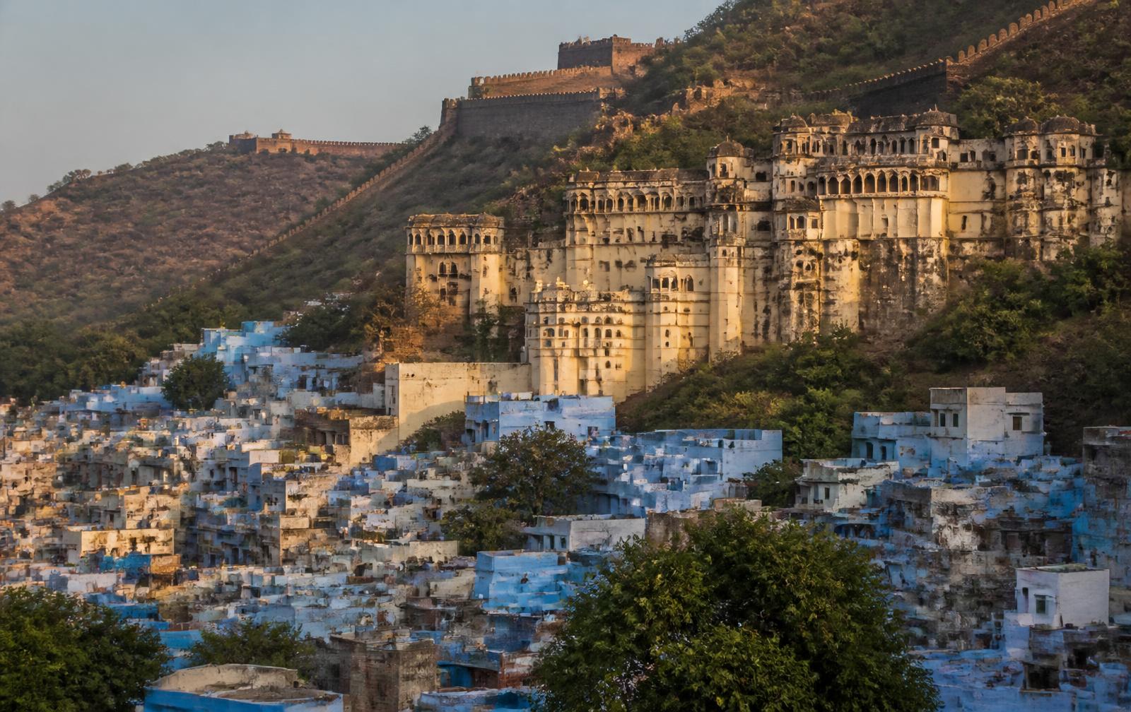 Blue-washed houses of Bundi in Rajasthan below the hilltop palace and fort in late afternoon light